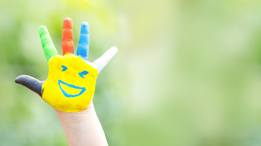 Bunte Hand, angemalt mit verschiedenen Farben als Gesicht