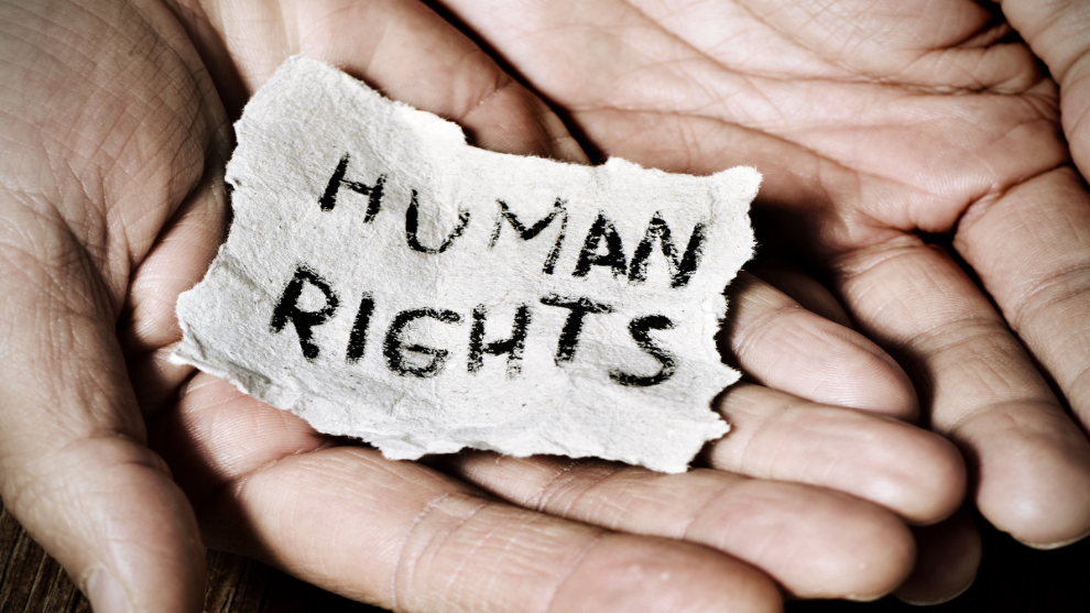 Hände halten ein Papier auf dem "Human Rights" steht