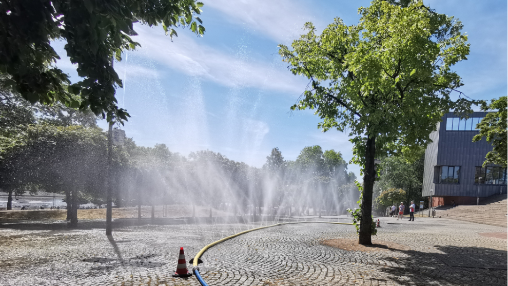 Wasserschlauch auf einem Platz aus dem Wassernebel spritzt