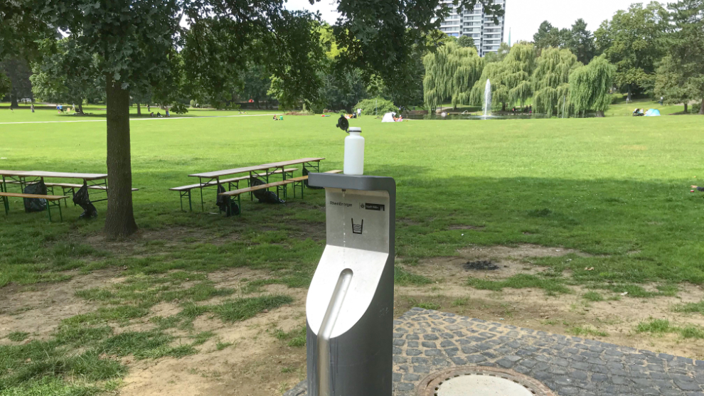Trinkwasserspender im Stadtpark Mülheim. Auf dem Trinkwasserspender steht eine leere Trinkflasche.
