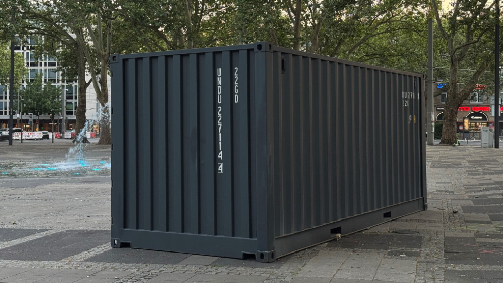 Foto von einem grauen Schiffscontainer, der vor dem Brunnen auf dem Neumarkt steht.