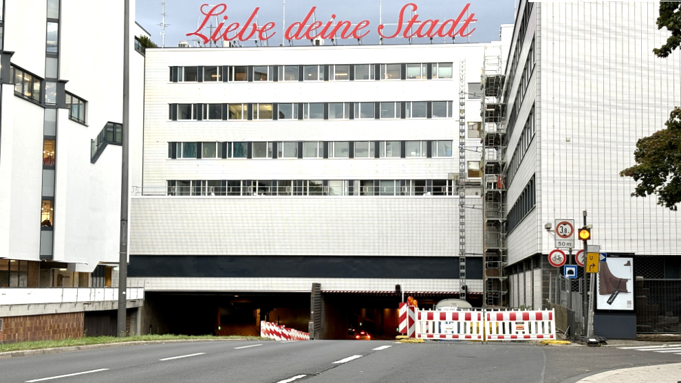Blick zur Einfahrt einen Tunnel unter der Schildergasse auf der Nord-Süd-Fahrt. Über einem Gebäude steht der Schriftzug Liebe deine Stadt.