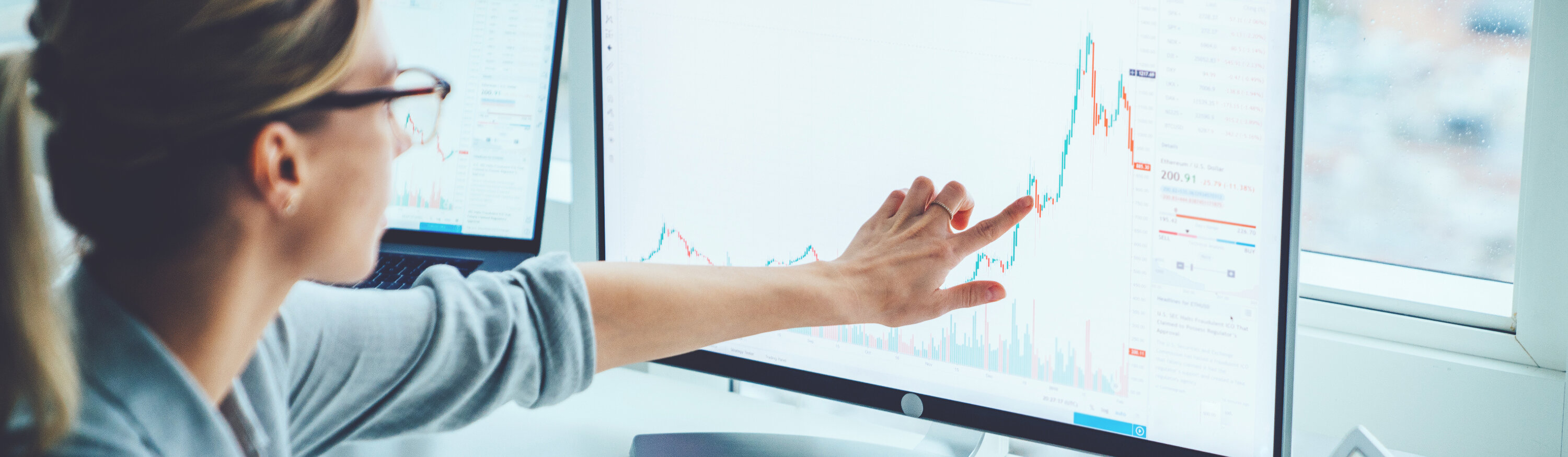 Frau deutet auf Statistikdiagramme auf Computerbildschirmen