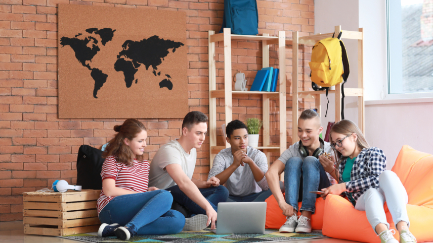 Gruppe Jugendlicher verbringen gemeinsam Zeit miteinander, sitzend auf dem Boden und Sitzsäcken., © Pixel-Shot – stock.adobe.com