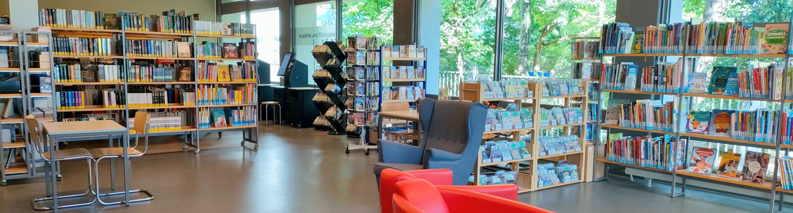 Innenansicht der Stadtteilbibliothek Bocklemünd; Sicht auf Bücherregale und einen roten Sessel, © Stadtbibliothek Köln